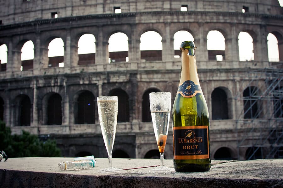 Taças e garrafa de champanhe com o Coliseu de fundo