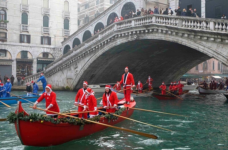 Pessoas com roupas de Natal andando de gôndola em canal de Veneza Pessoas com roupas de Natal andando de gôndola em canal de Veneza